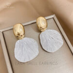 Elevate your style with our Lana Shell Earrings by Sodashi. These exquisite drop earrings blend the timeless elegance of gold and silver, creating a stunning vintage-inspired design. The chunky shell motif adds a bold touch, perfect for making a statement. Crafted from high-quality zinc alloy, these earrings offer both durability and a luxurious feel. Whether you're dressing up for a special occasion or adding a chic twist to your everyday look, the Lana Shell Earrings are your go-to accessory. Shine effortlessly with the perfect mix of classic charm and modern sophistication. #SodashiJewelry #VintageChic #StatementEarrings #GoldAndSilver