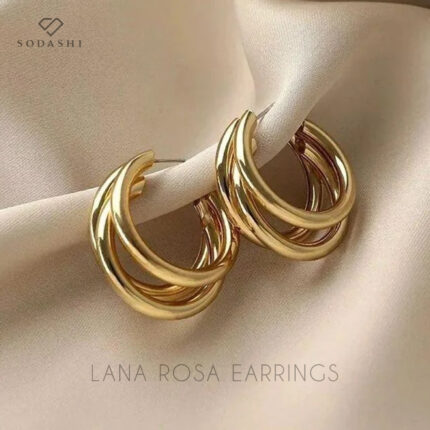 Discover the exquisite Lana Rosa earrings by Sodashi, designed to elevate your style with their unique blend of elegance and vintage charm. These triple hoops seamlessly merge into one bold, chunky earring, creating a standout accessory perfect for any occasion. Available in both gold and silver plating, the Lana Rosa earrings are crafted from high-quality zinc alloy, ensuring durability and lasting shine. Measuring 3CM in both length and width, these earrings offer a versatile addition to your jewelry collection, effortlessly complementing any outfit. Embrace the timeless appeal of the Lana Rosa earrings and make a sophisticated statement.